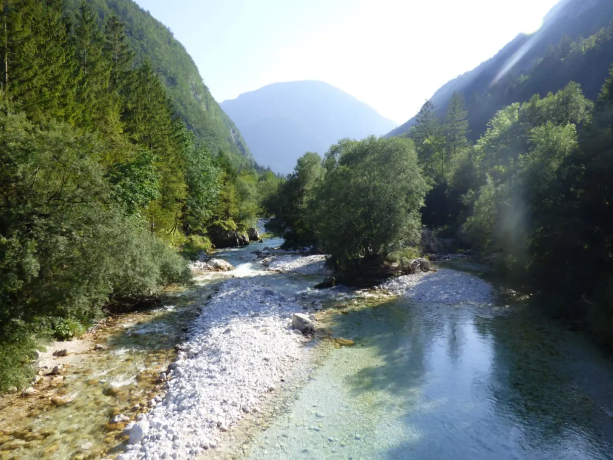 Wide river lined with white pebbles between two slopes