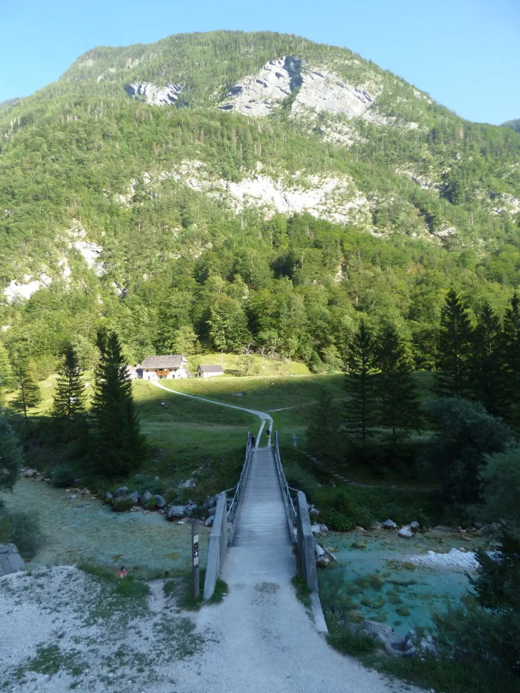 Wooden footbridge crossing the river towards an isolated chalet