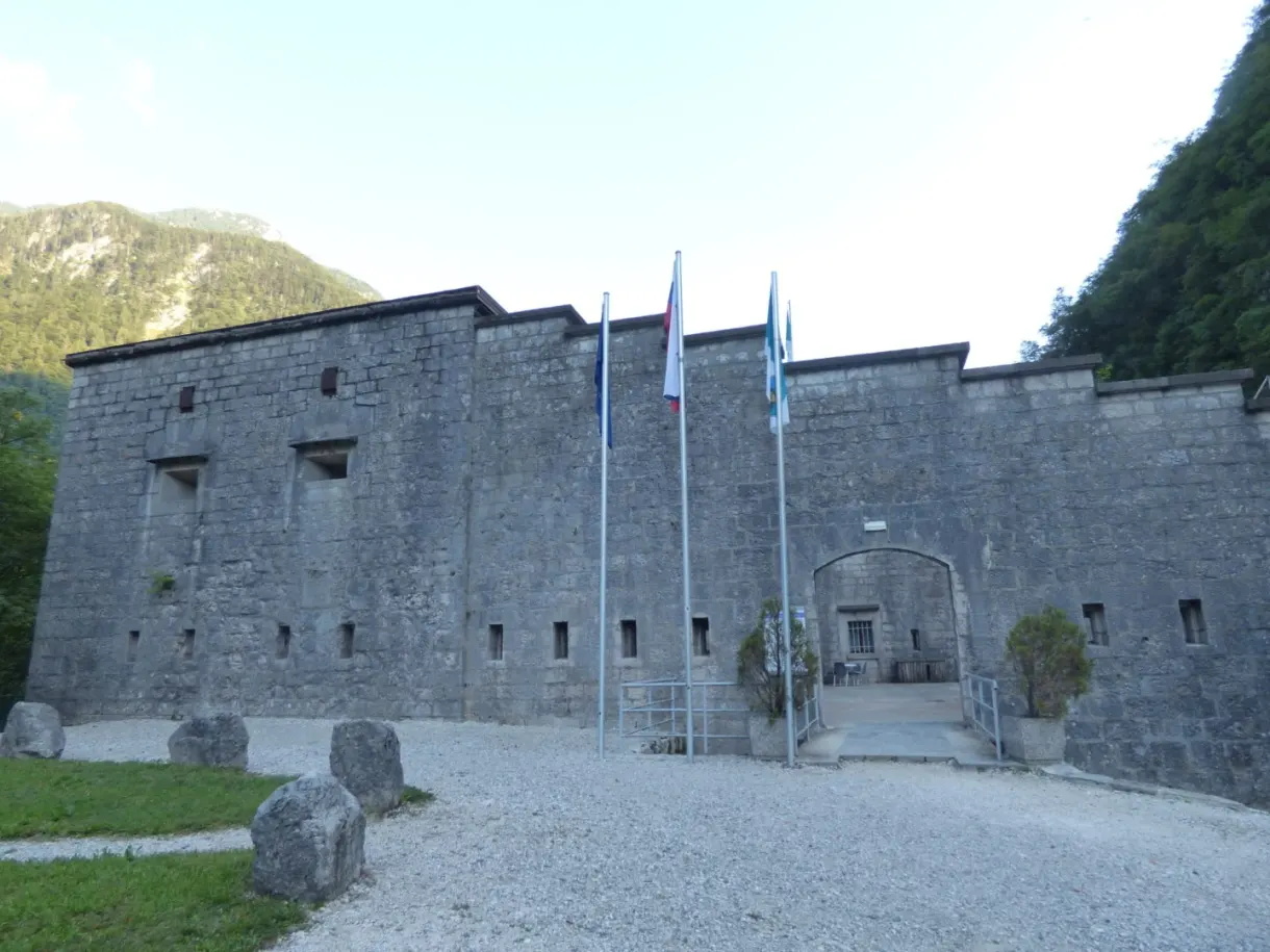 Facade of the Kluže fort and its flags on a gravel courtyard
