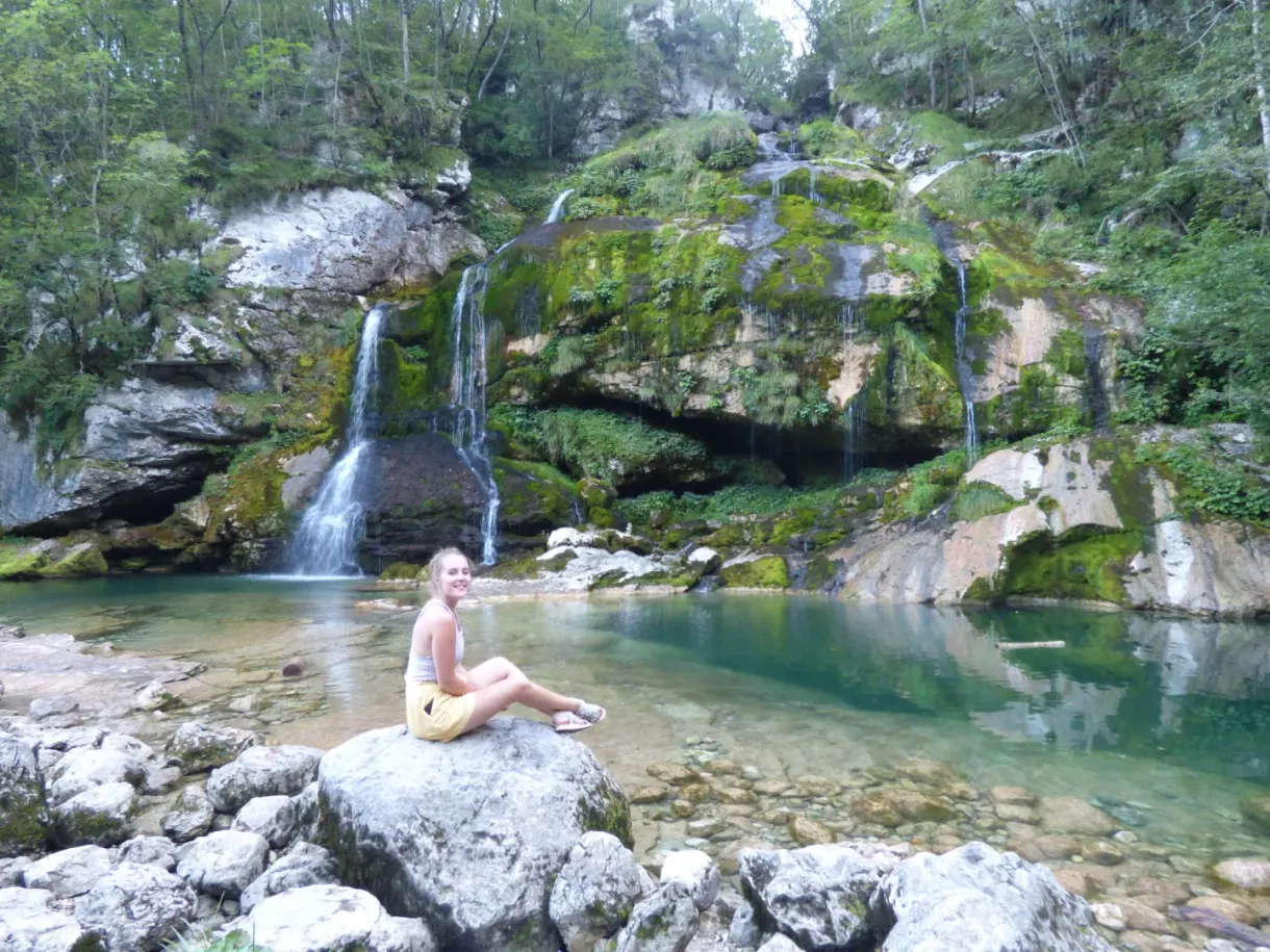 Sitting on a rock in front of the waterfall and its turquoise pool