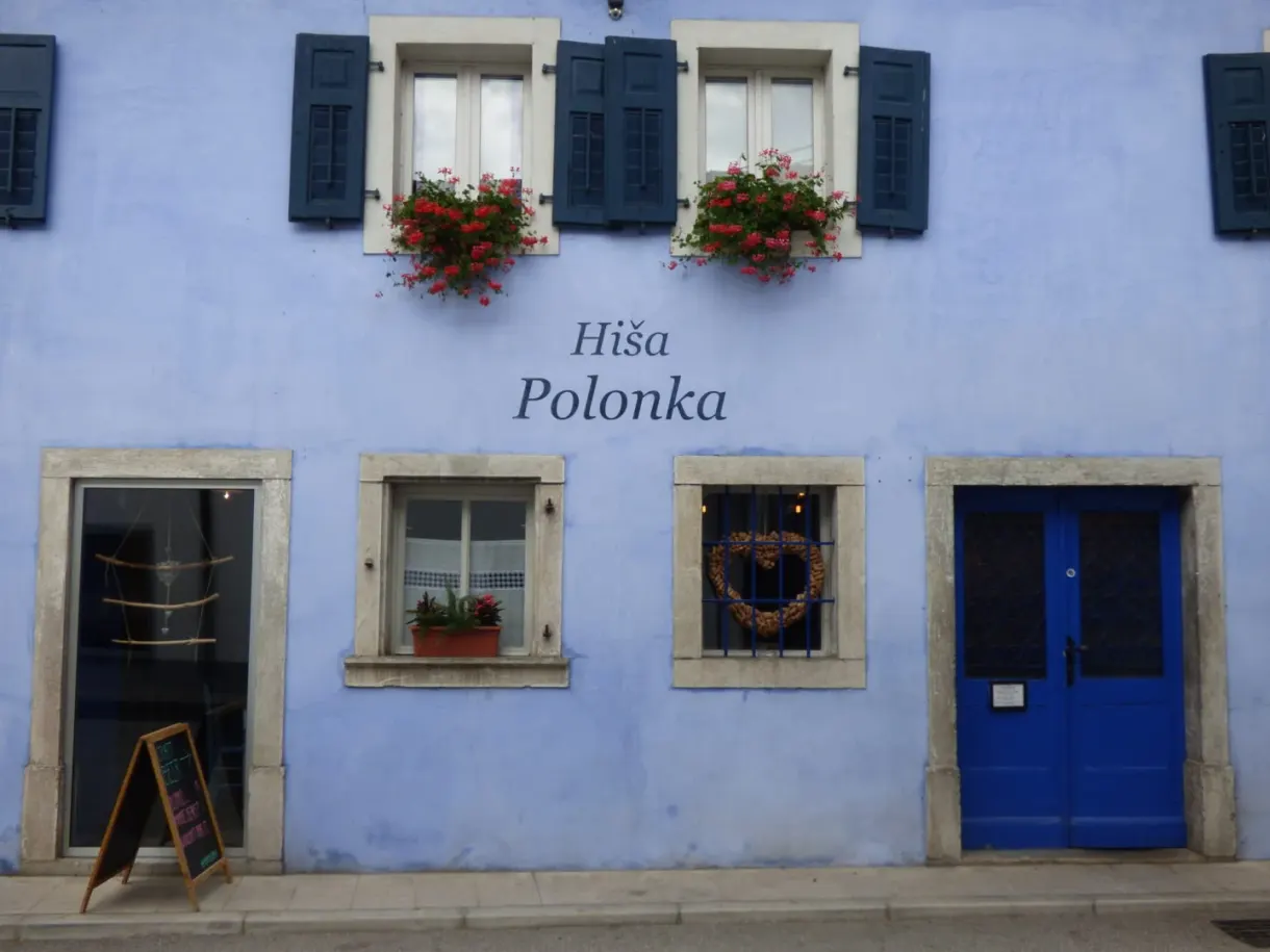 Mauve facade of a restaurant with blue shutters and door