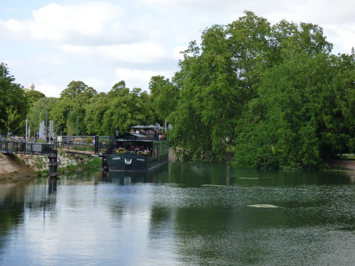 Canal arboré avec péniche bar et jet d'eau