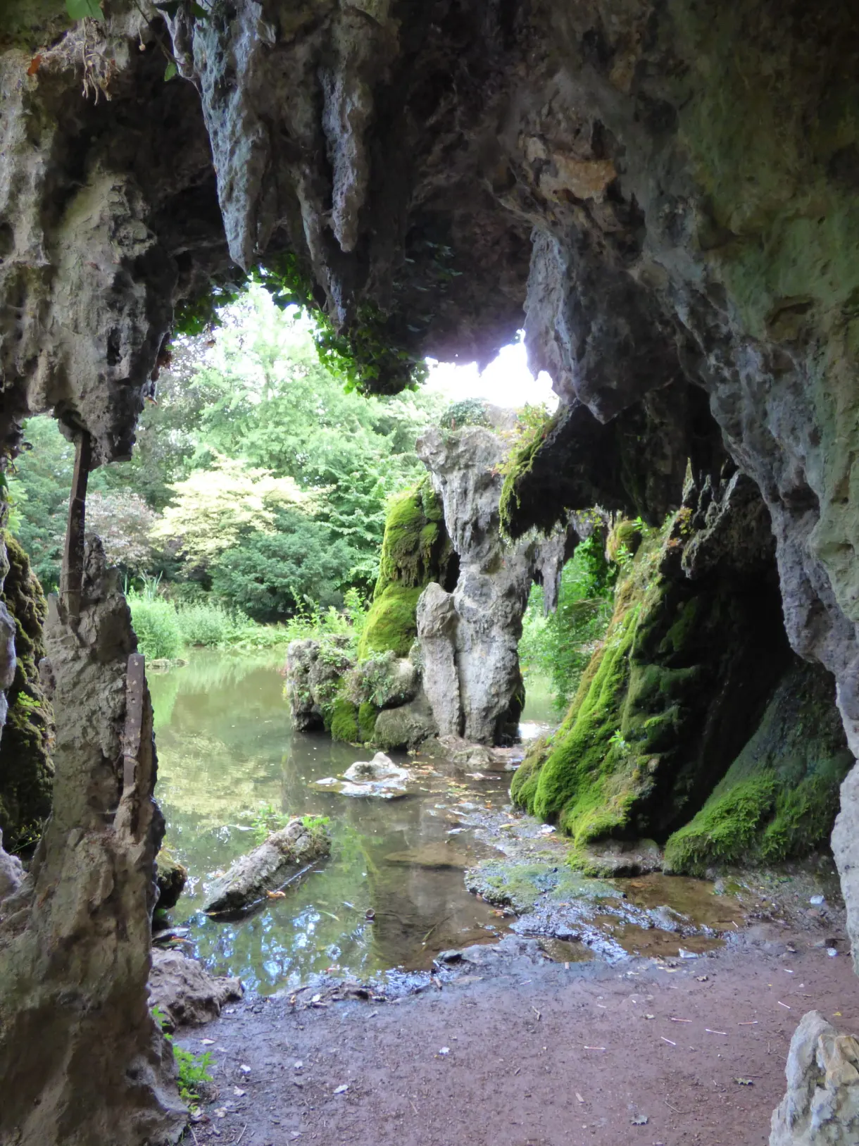 Grotte artificielle moussue traversée par un filet d'eau