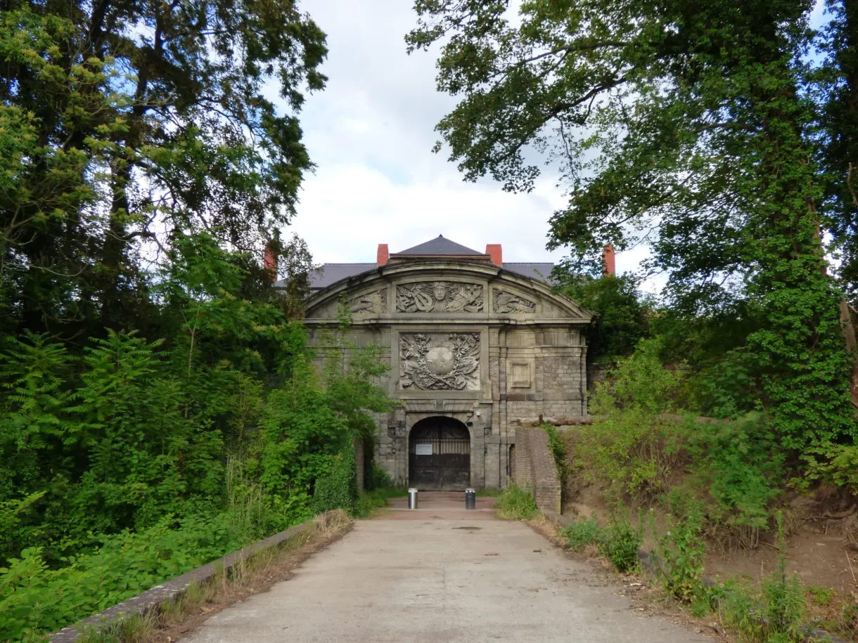 Porte monumentale sculptée au bout d'un chemin ombragé