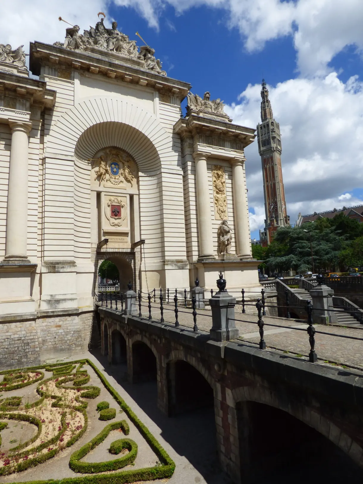 Porte de Paris de biais avec beffroi et jardins à la française