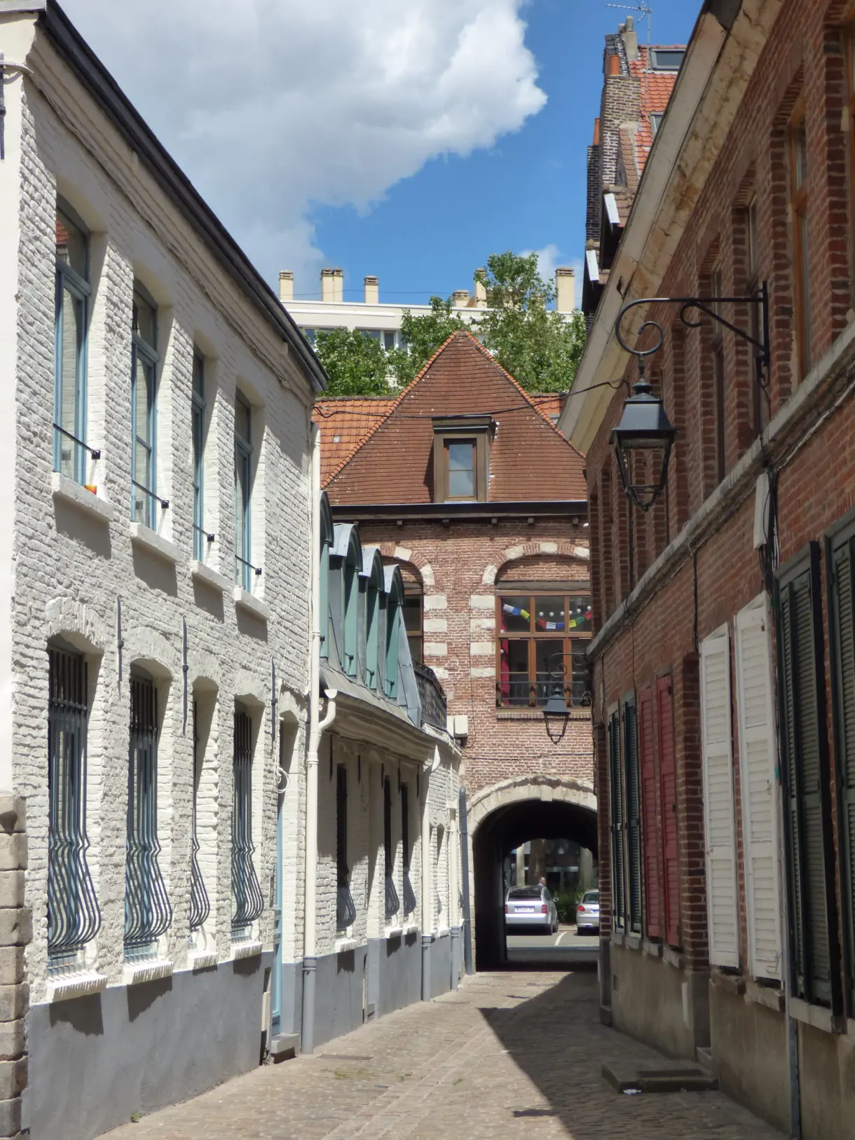 Rue aux façades claires ouvrant sur un passage voûté
