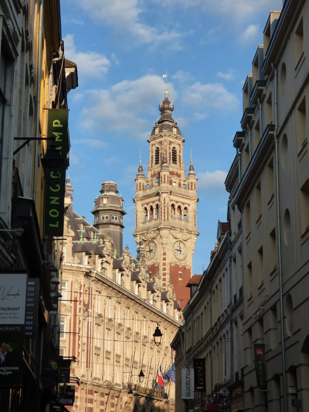 Enseignes de commerces et beffroi au bout de la rue