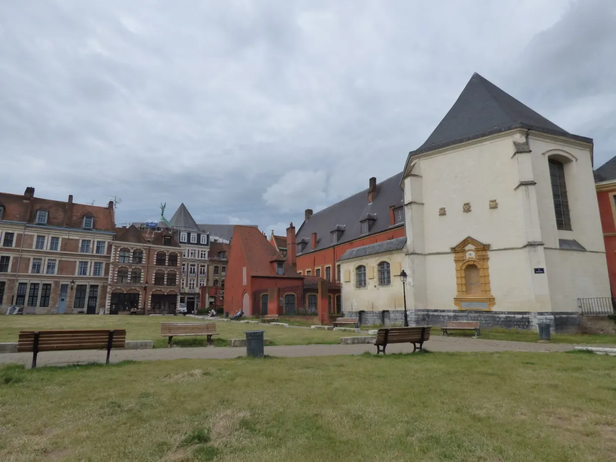 Chapelle blanche et bancs de bois au bout d'une pelouse