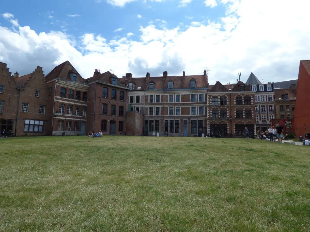 Long bâtiment de brique derrière une large étendue d'herbe