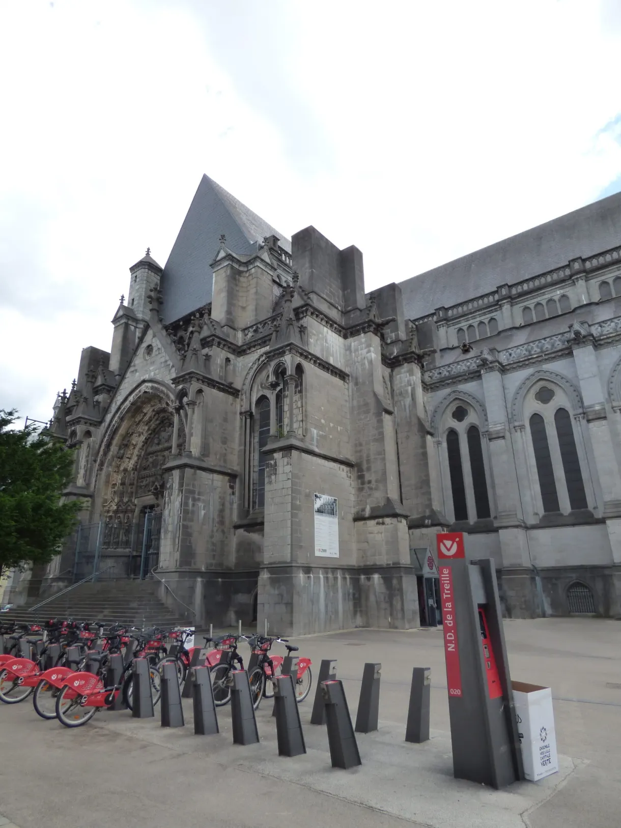 Flanc gothique et porche sculpté devant des vélos en libre service