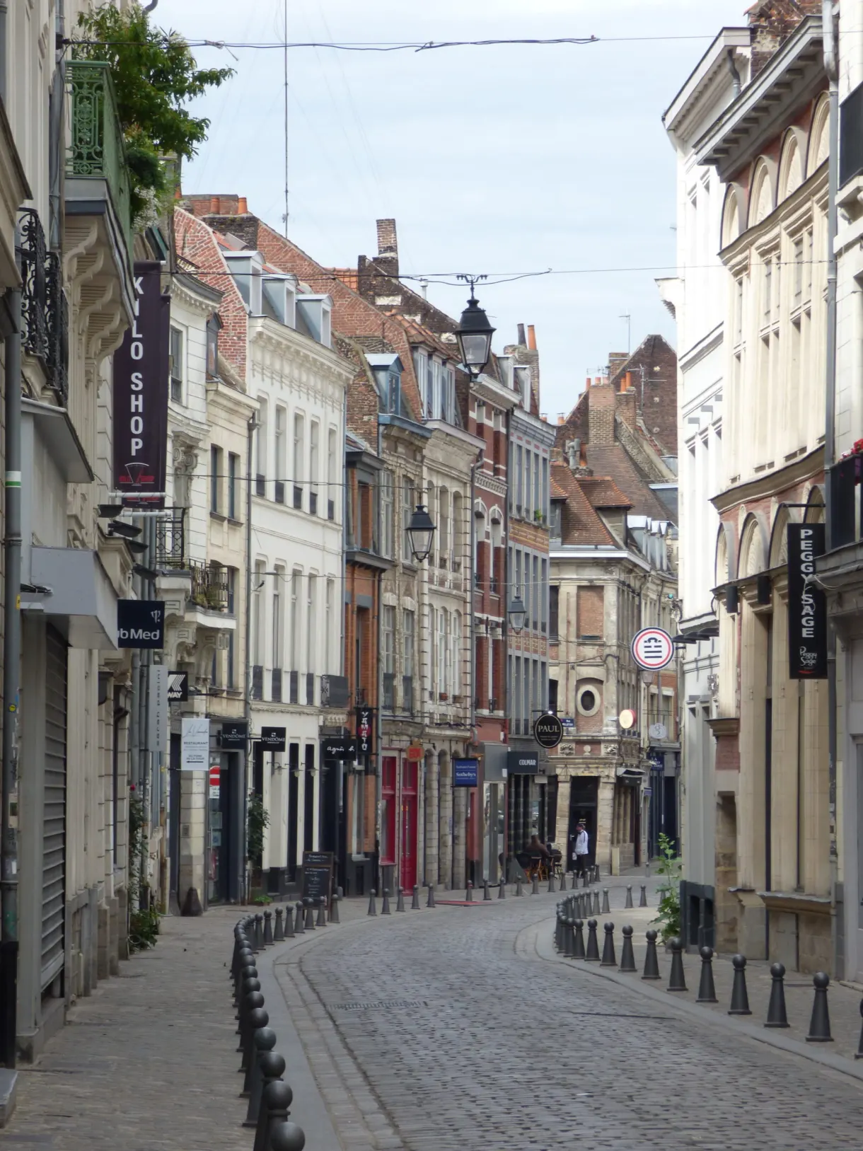 Rue commerçante en descente bordée de vitrines