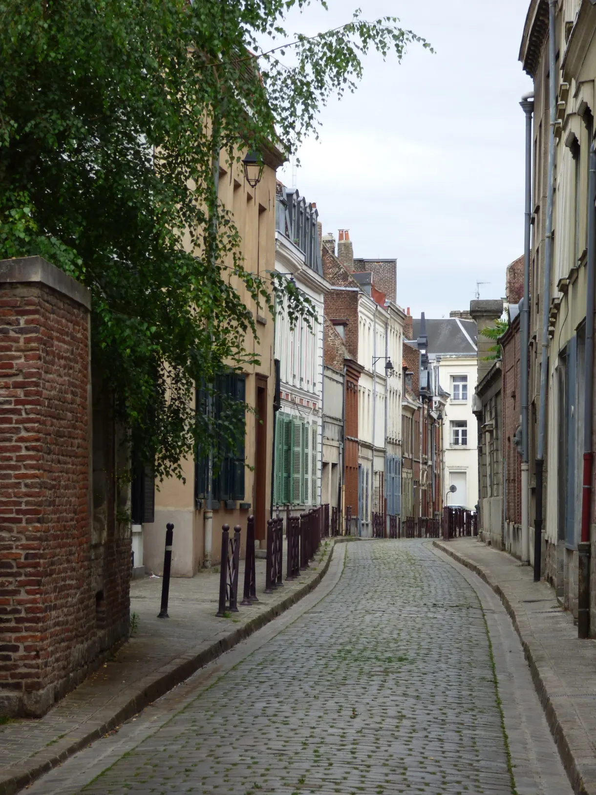 Ruelle pavée entre murs de brique et volets verts