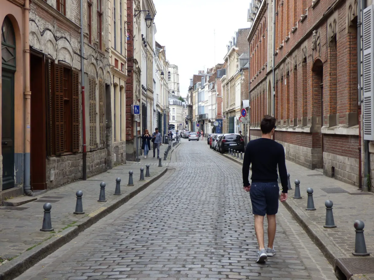 Homme marchant sur les pavés entre deux rangées de bornes