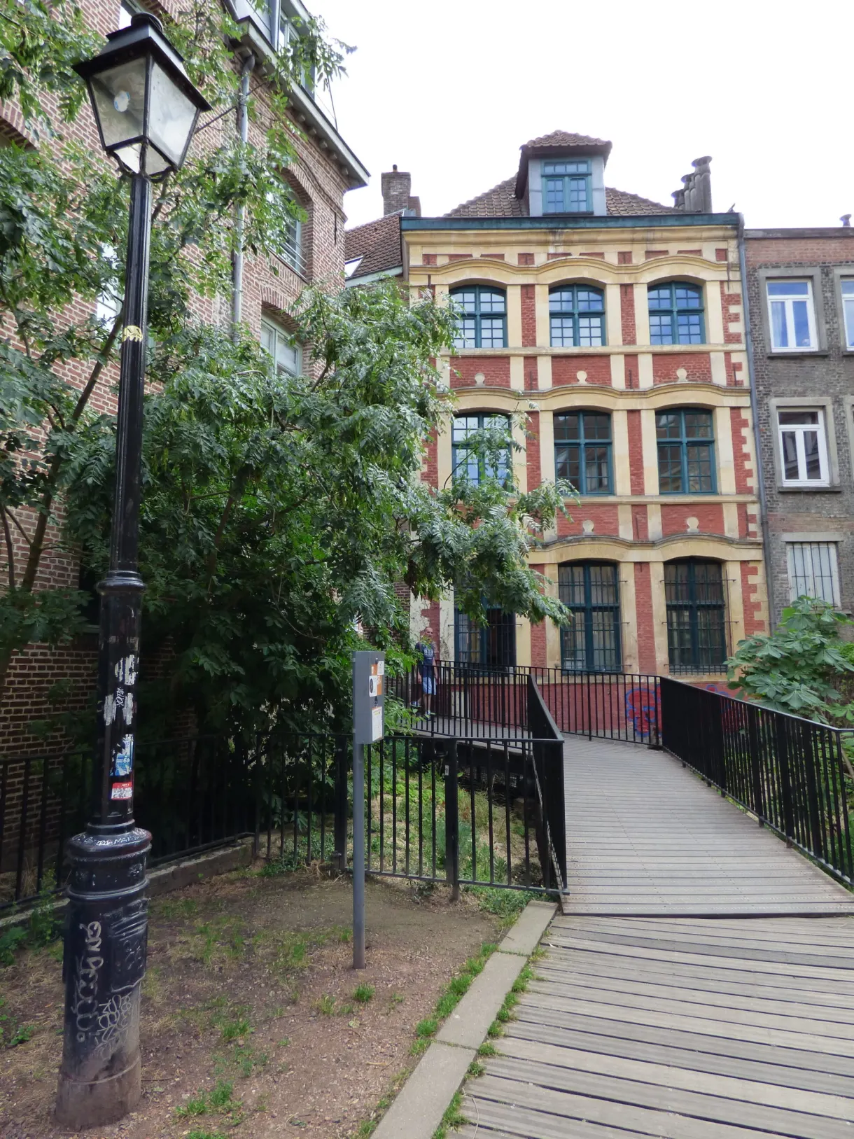 Maisons colorées aperçues derrière une grille et un arbre