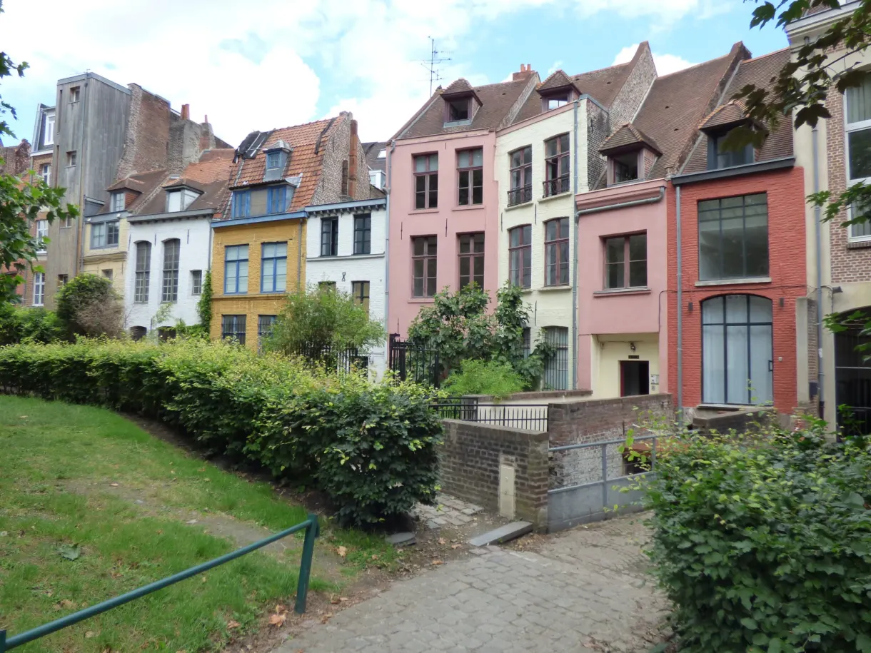 Maisons rose, jaune et bordeaux au-dessus d'un talus