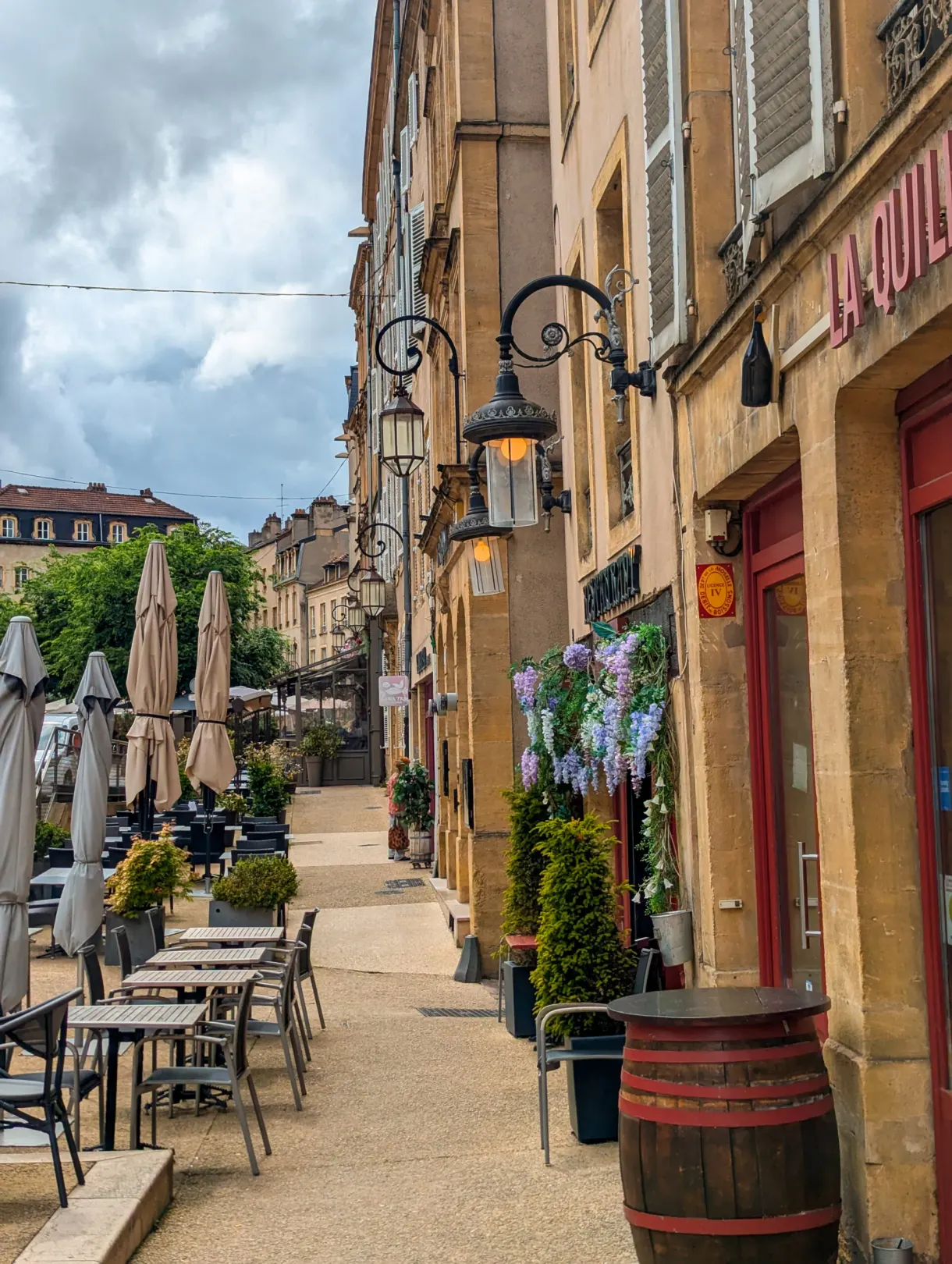 Ruelle du quartier des Îles bordée de terrasses, lanternes en fer forgé et tonneau