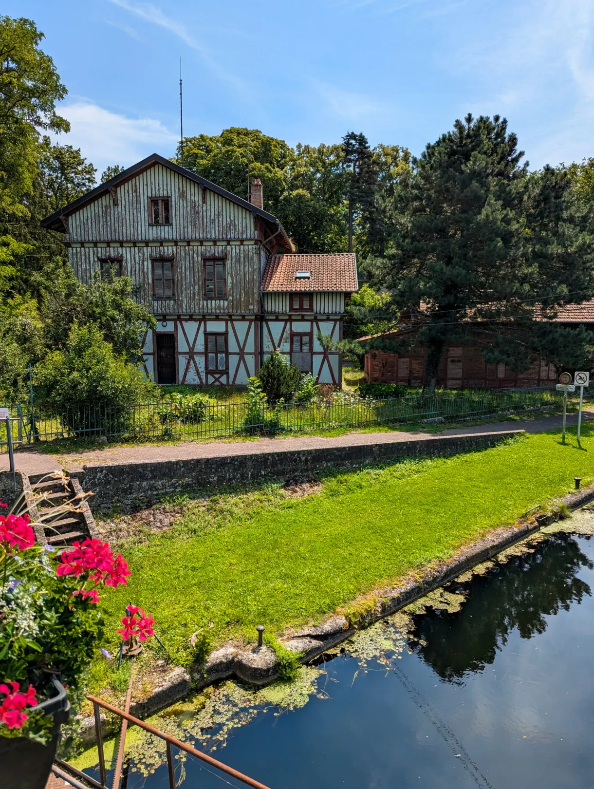 Maison à colombages au bord d'un canal, massif de fleurs rouges