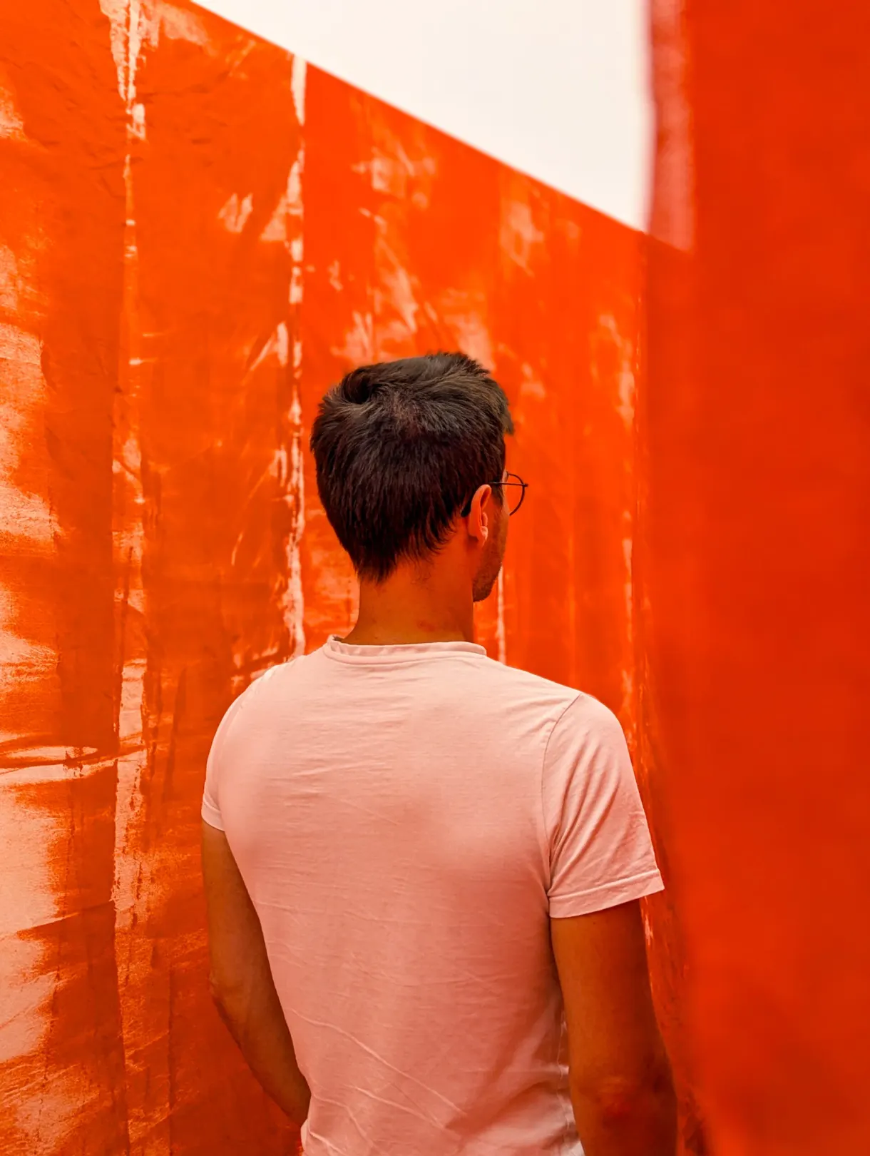 Visiteur de dos devant une immense bâche orange tendue en salle
