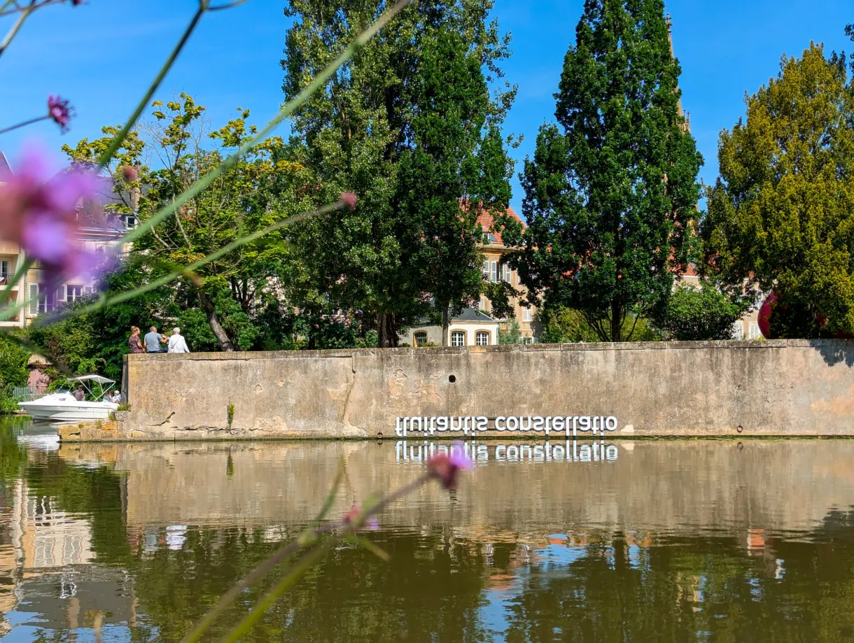 Inscription blanche sur un mur de quai, reflétée dans l'eau calme
