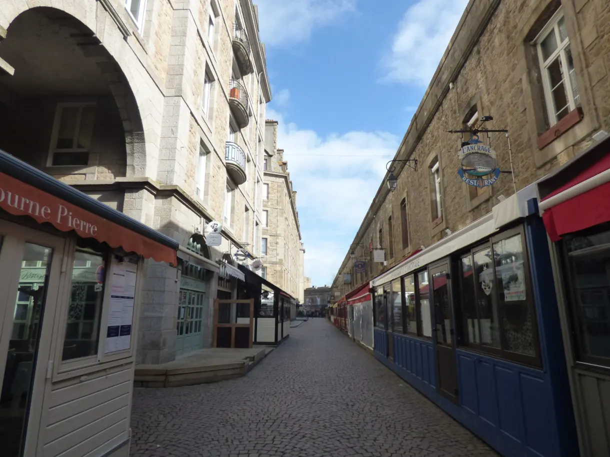 Ruelle pavée intra-muros bordée de devantures de commerces