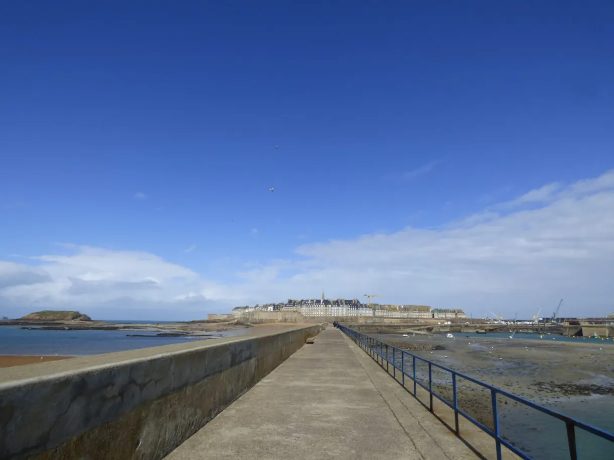 Jetée bétonnée pointant vers un îlot à marée basse