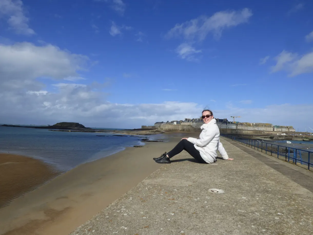 Visiteuse assise au bout de la jetée face à la baie