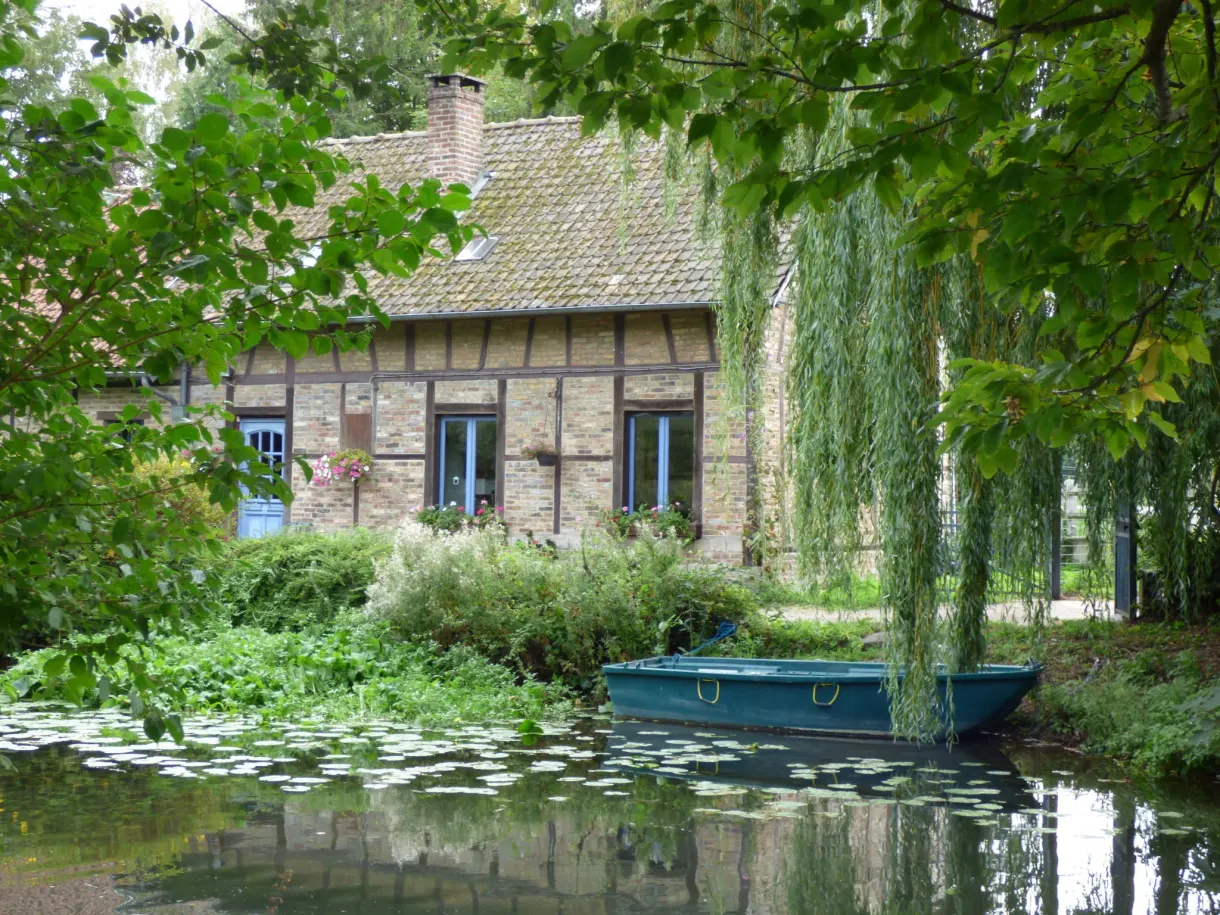 Half timbered house at the water's edge and a green boat moored