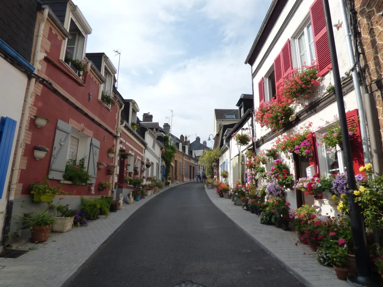Sloping lane lined with flower decked houses with red shutters