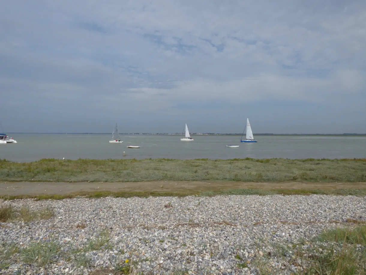Sailing boats offshore above a pebble foreshore