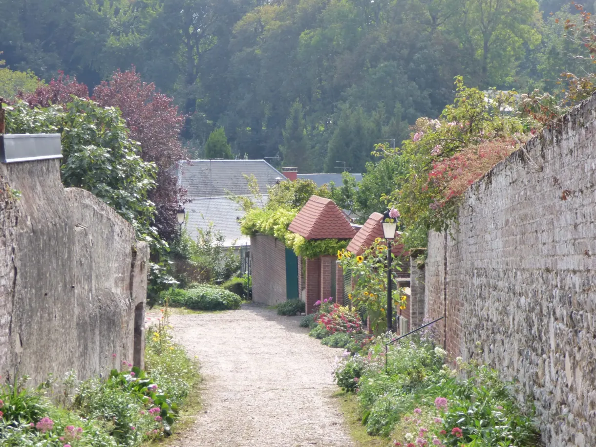 Path between two high stone walls covered with flowers