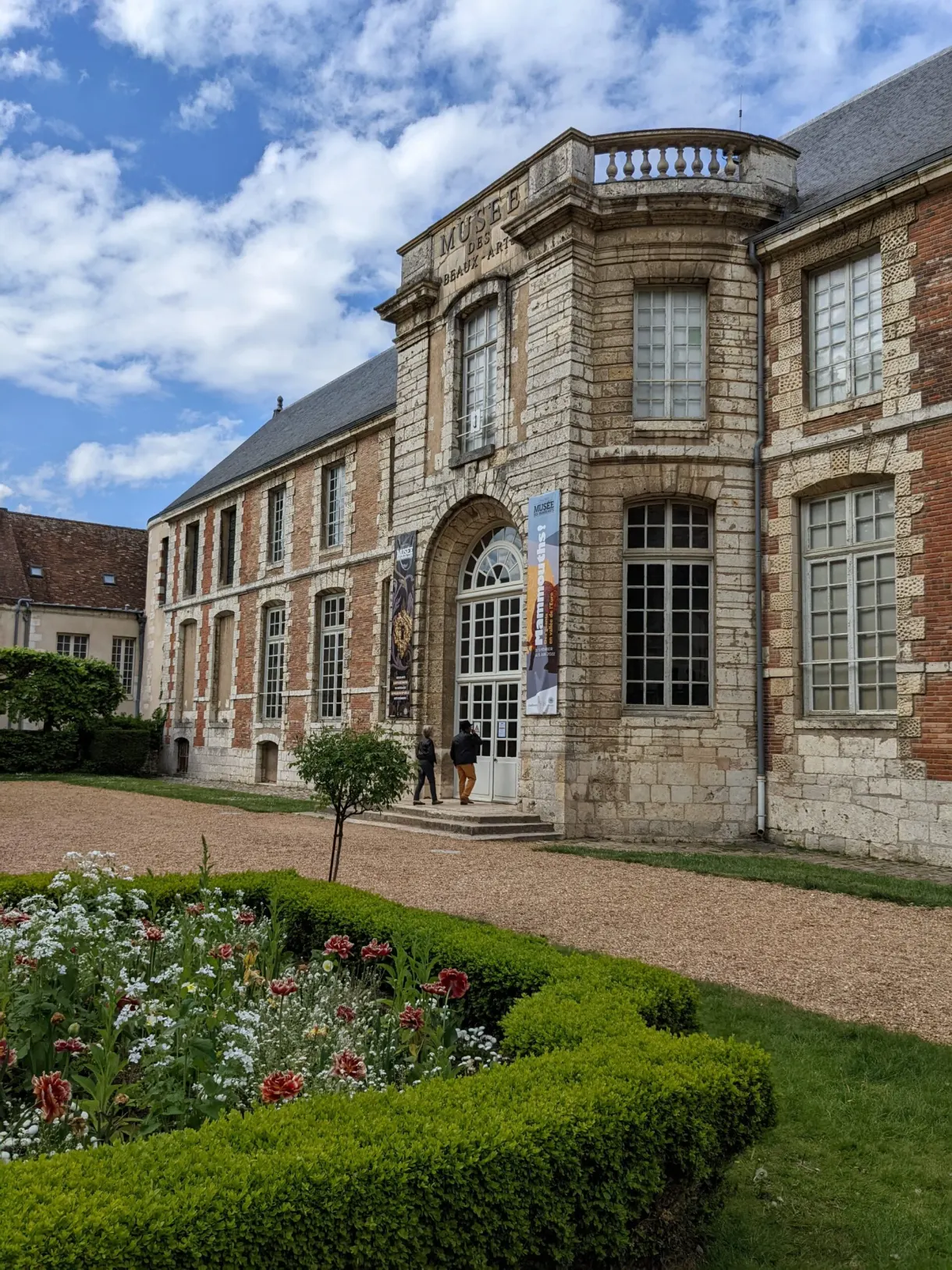 Façade classique d'un hôtel particulier devant ses parterres de rosiers