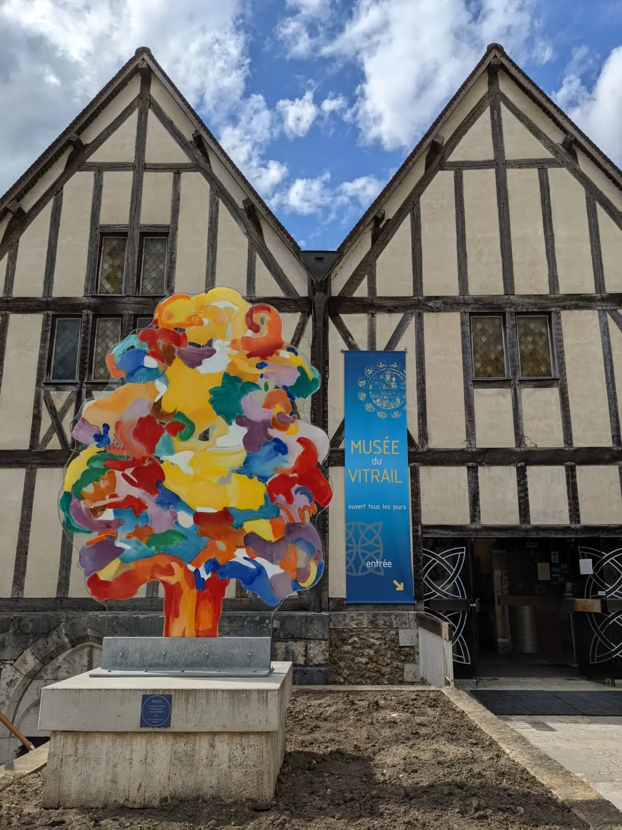 Sculpture multicolore devant une maison à colombages du centre