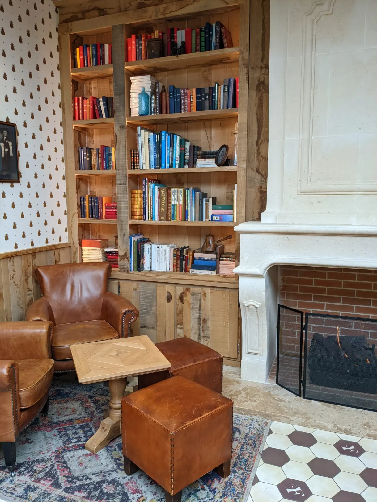 Salon d'hôtel avec bibliothèque, fauteuils de cuir et cheminée